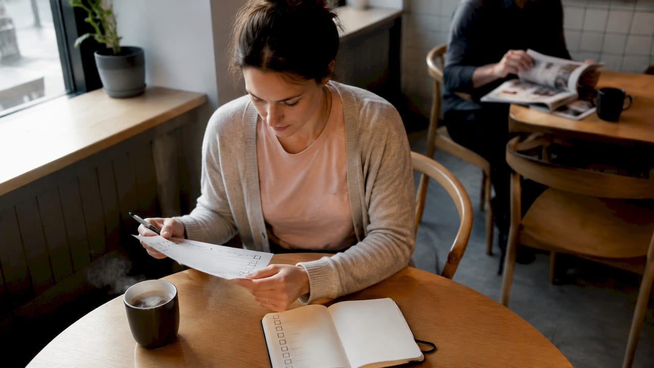 Une femme passe en revue sa liste de critères pour choisir un nouvel ordinateur portable, confortablement installée chez elle.