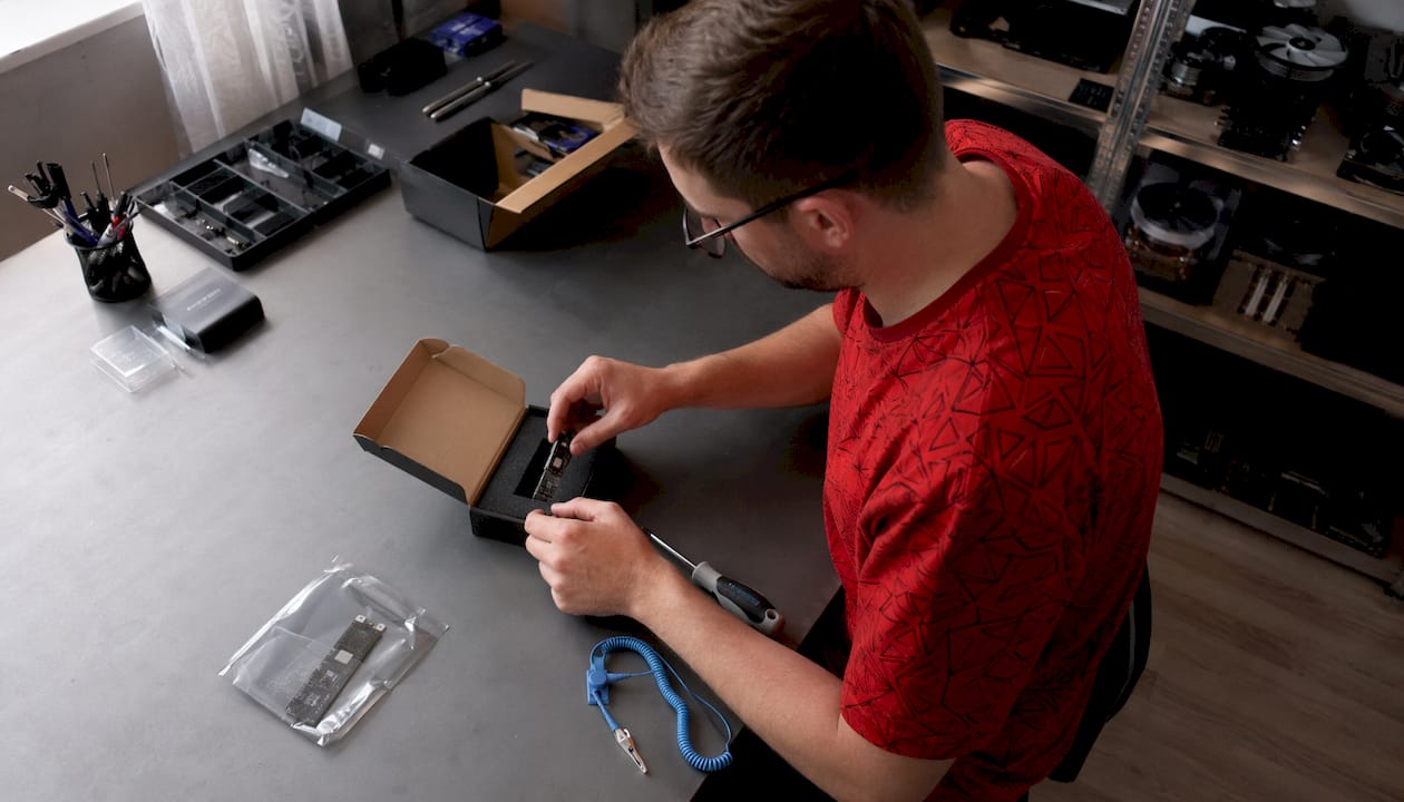 Un homme inspecte un SSD NVMe avant de le monter dans son ordinateur.