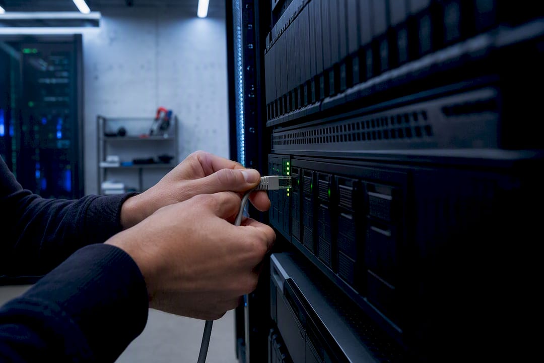 Des mains branchent un câble réseau sur un serveur de stockage NAS.