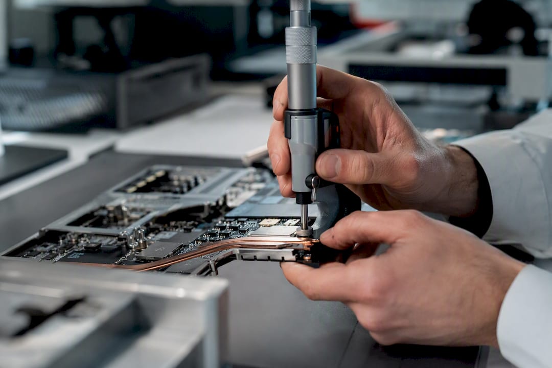 Mains mesurant du matériel informatique en laboratoire de contrôle qualité