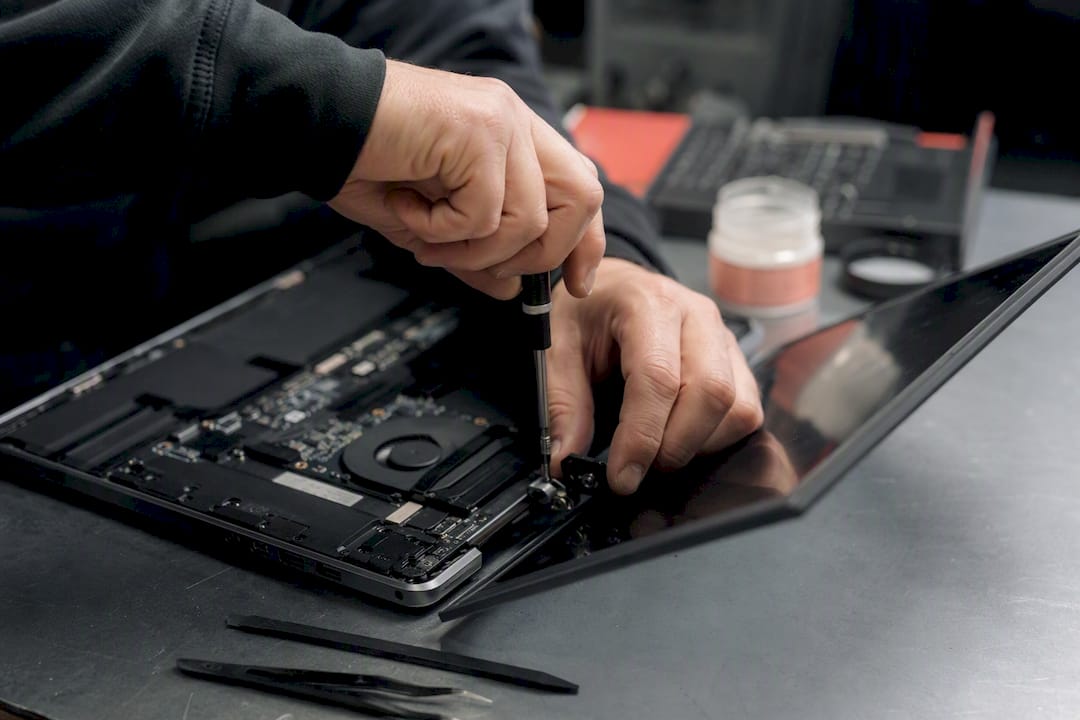 Gros plan sur des mains réparant la charnière d'un ordinateur portable